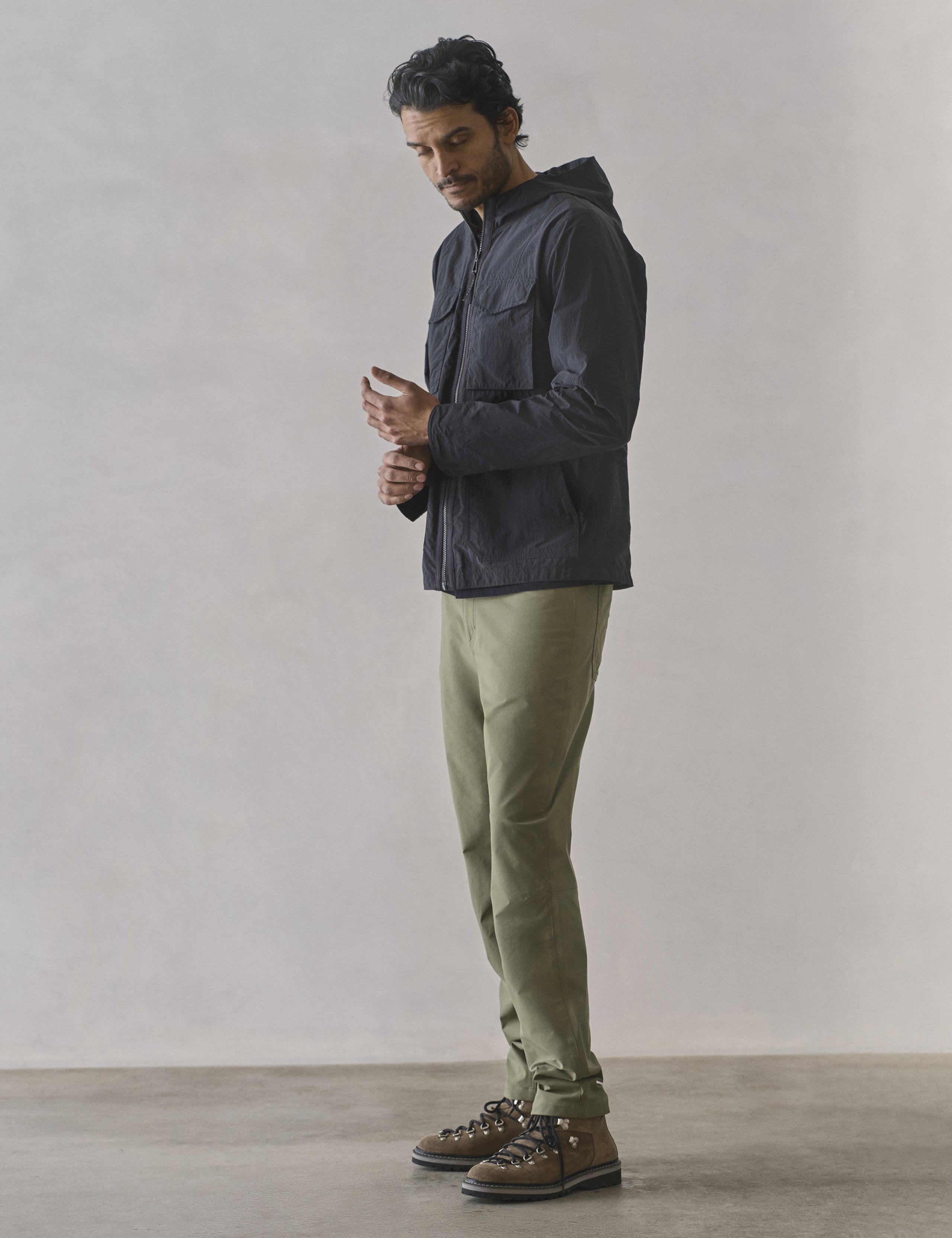 Full-body side profile view of man wearing Aires Lightweight Windbreaker in Onyx Black from AETHER Apparel.