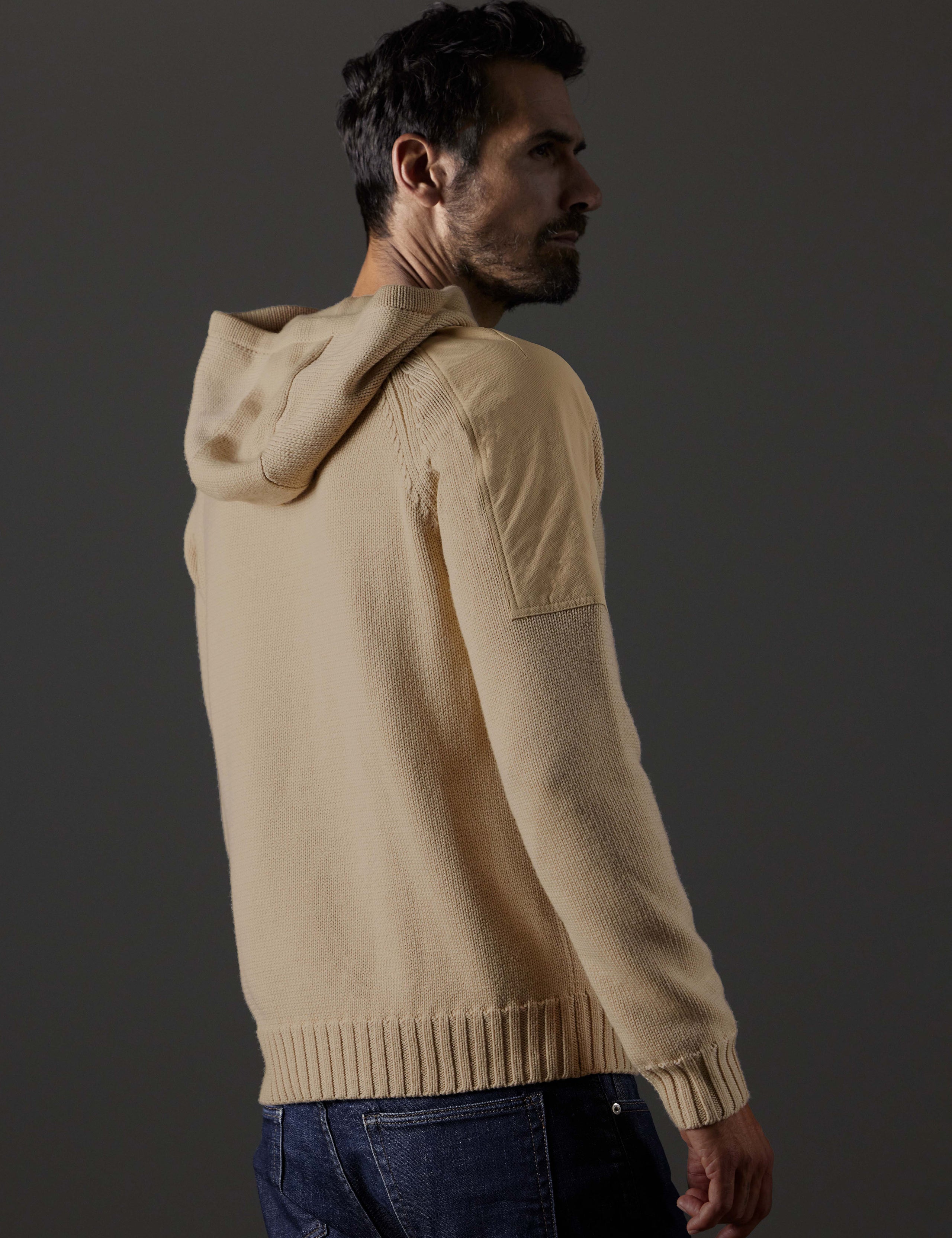 Rear 3/4 body view of man wearing Benson Hooded Sweater in Oatmeal beige from AETHER Apparel.