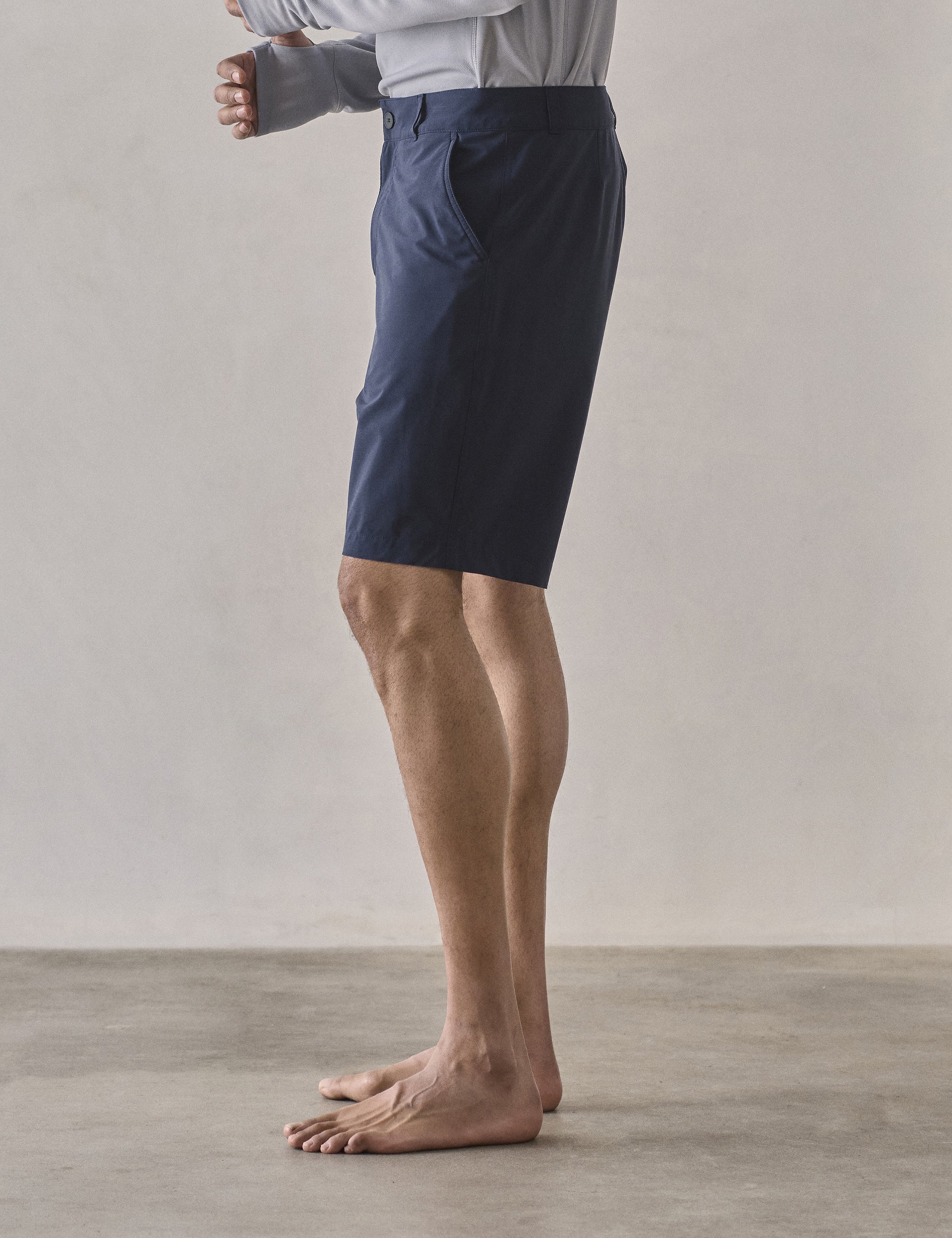 Left side profile lower-body view of man wearing Catalina Submersible Short in Total Eclipse dark blue from AETHER Apparel.