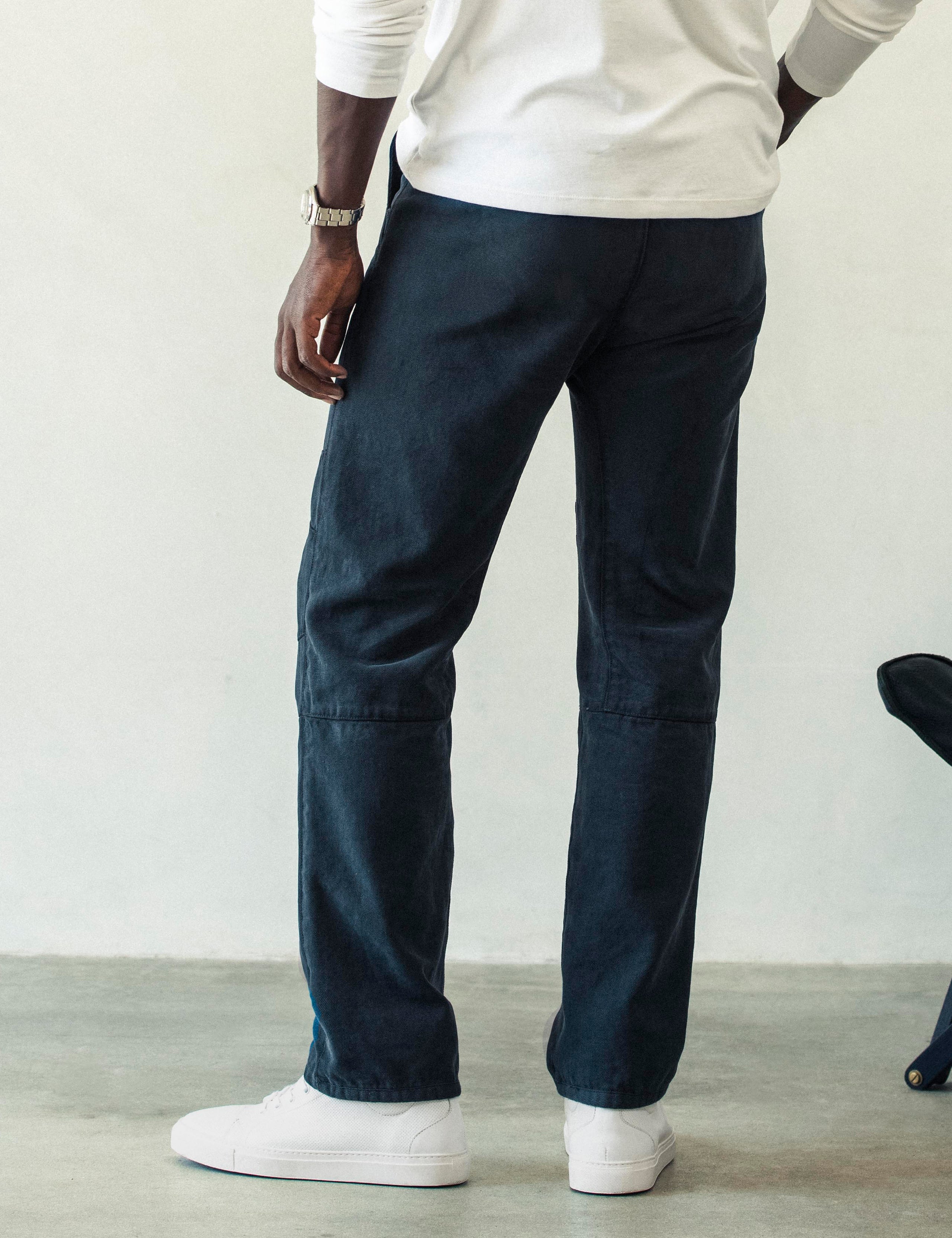 Rear angled lower body view of man wearing Gabriel Articulated Chino Stretch pant in Total Eclipse dark blue from AETHER Apparel.