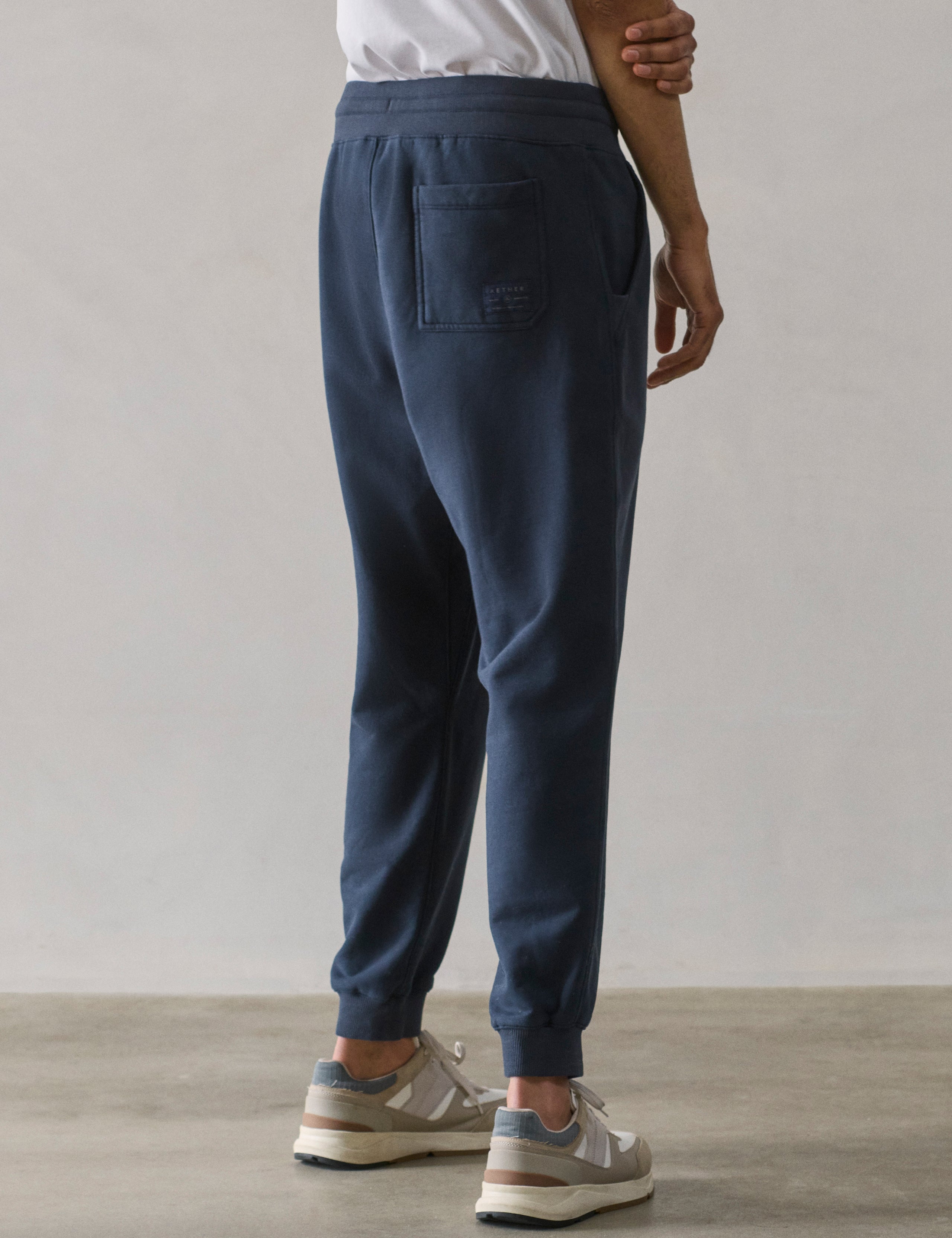 Rear 3/4 lower body view of man wearing Osa Cuffed Sweatpant in Total Eclipse dark blue from AETHER Apparel.