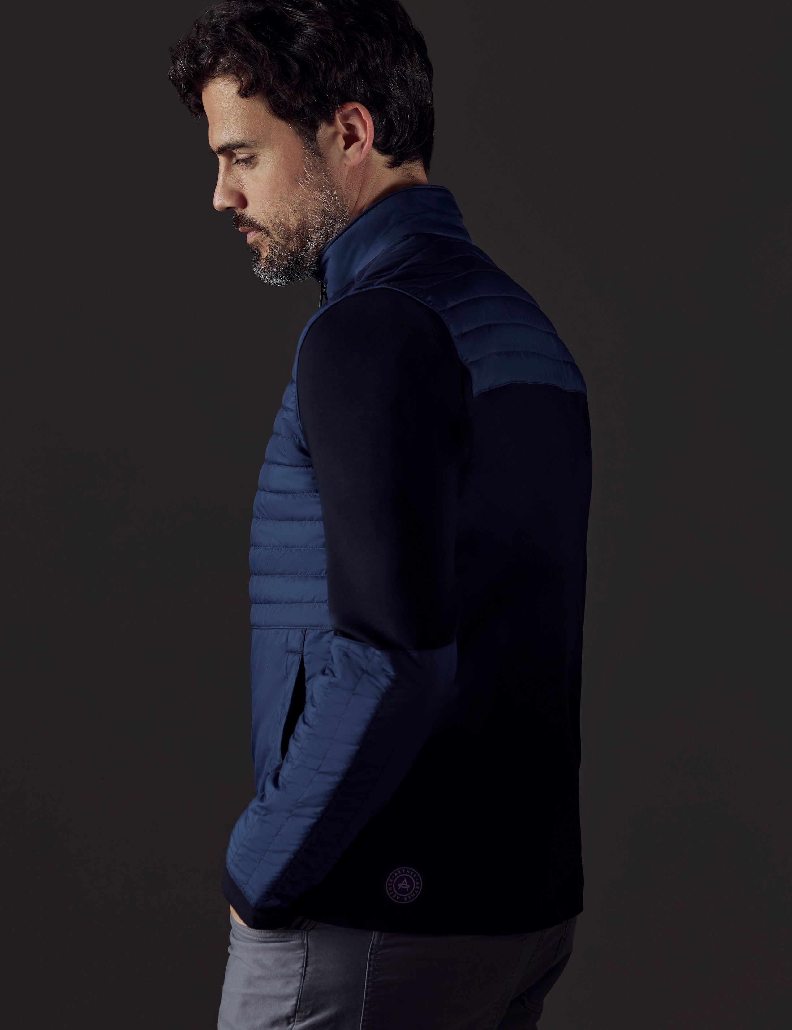 Side profile body view of man wearing Watts Technical Jacket in Total Eclipse dark blue from AETHER Apparel.