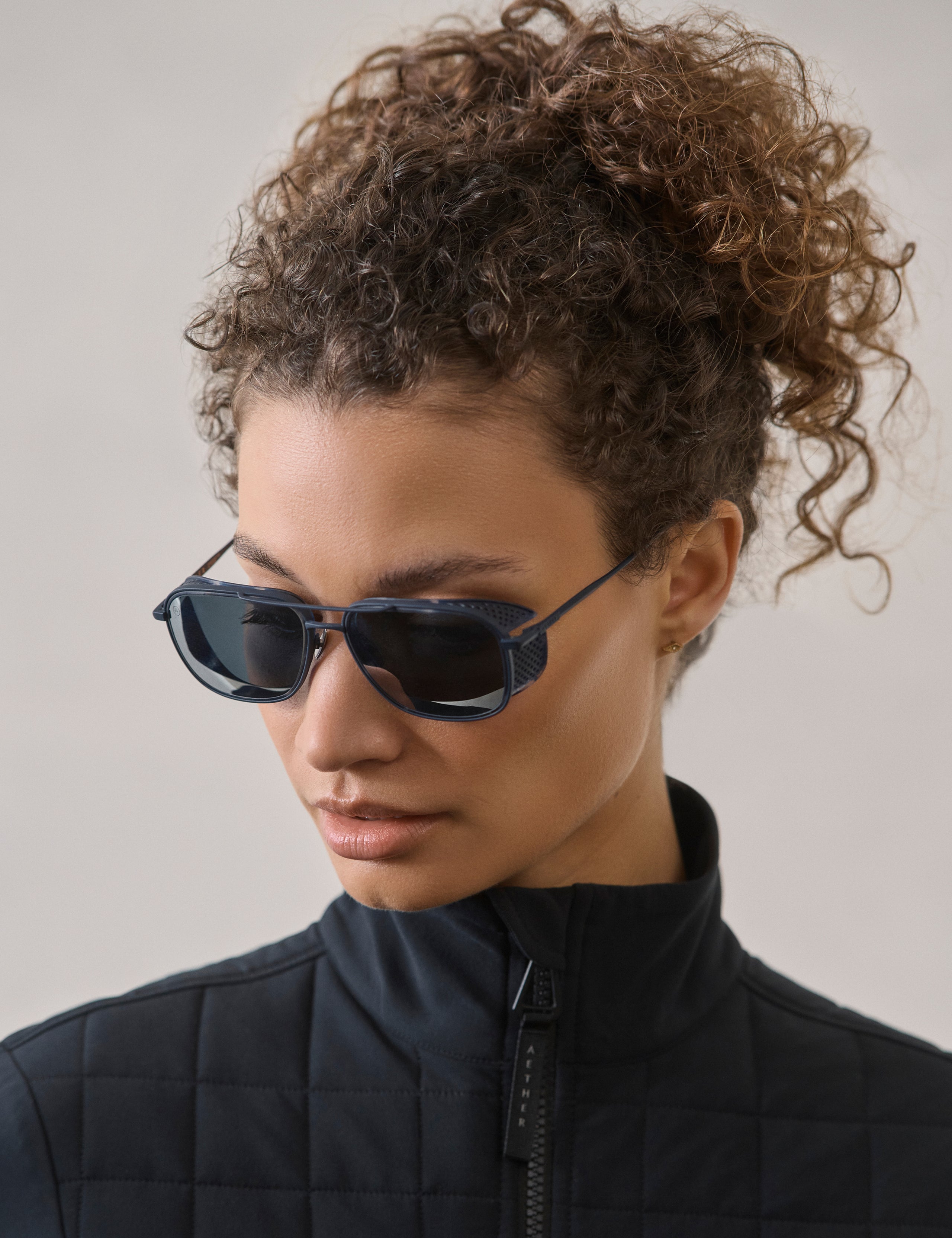 Front 3/4 view of woman wearing Summit Sunglass in Blue titanium with Blue Lens from AETHER Apparel.