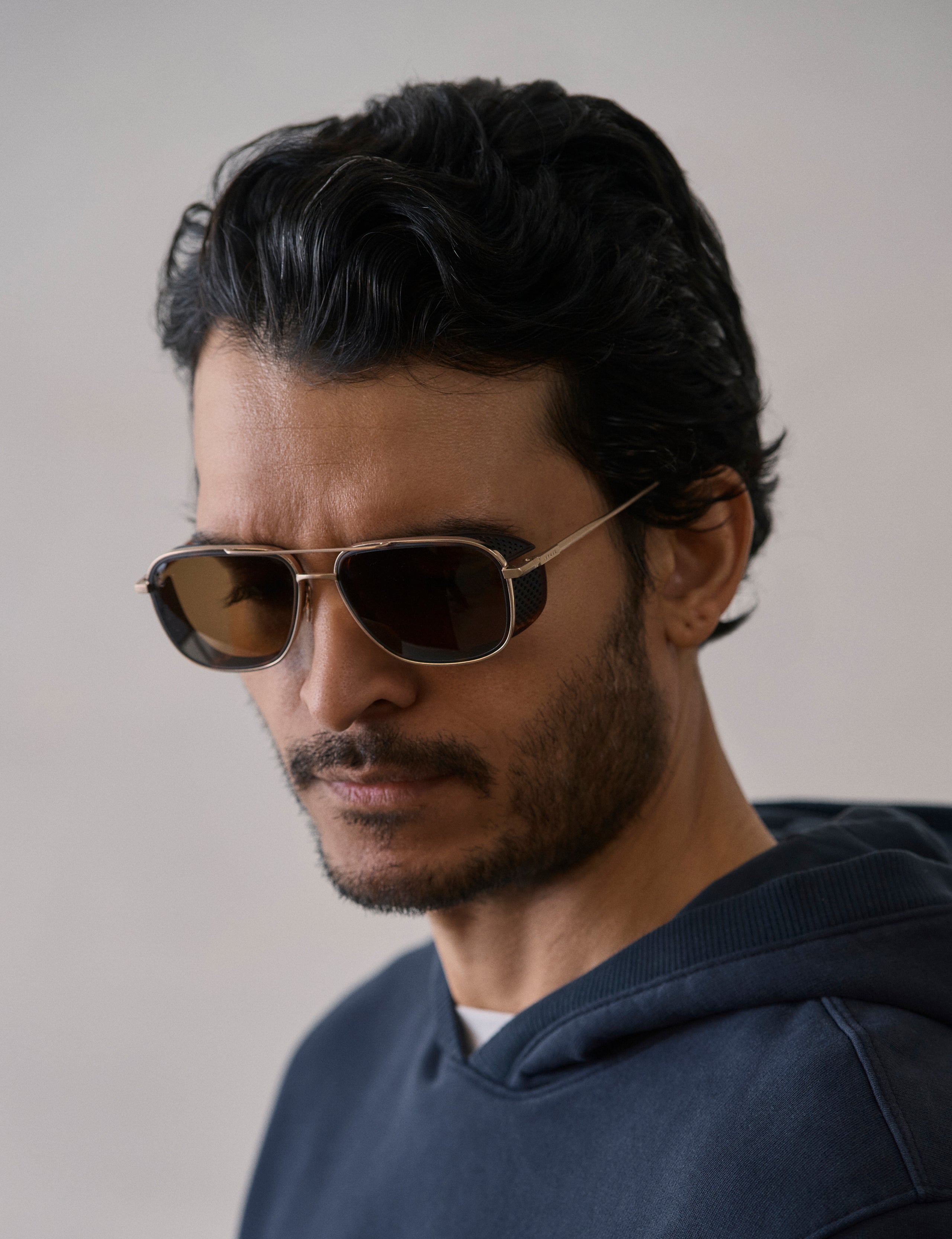 Front 3/4 view of man wearing Summit Sunglass in Brushed Gold titanium with G15 Lens from AETHER Apparel.