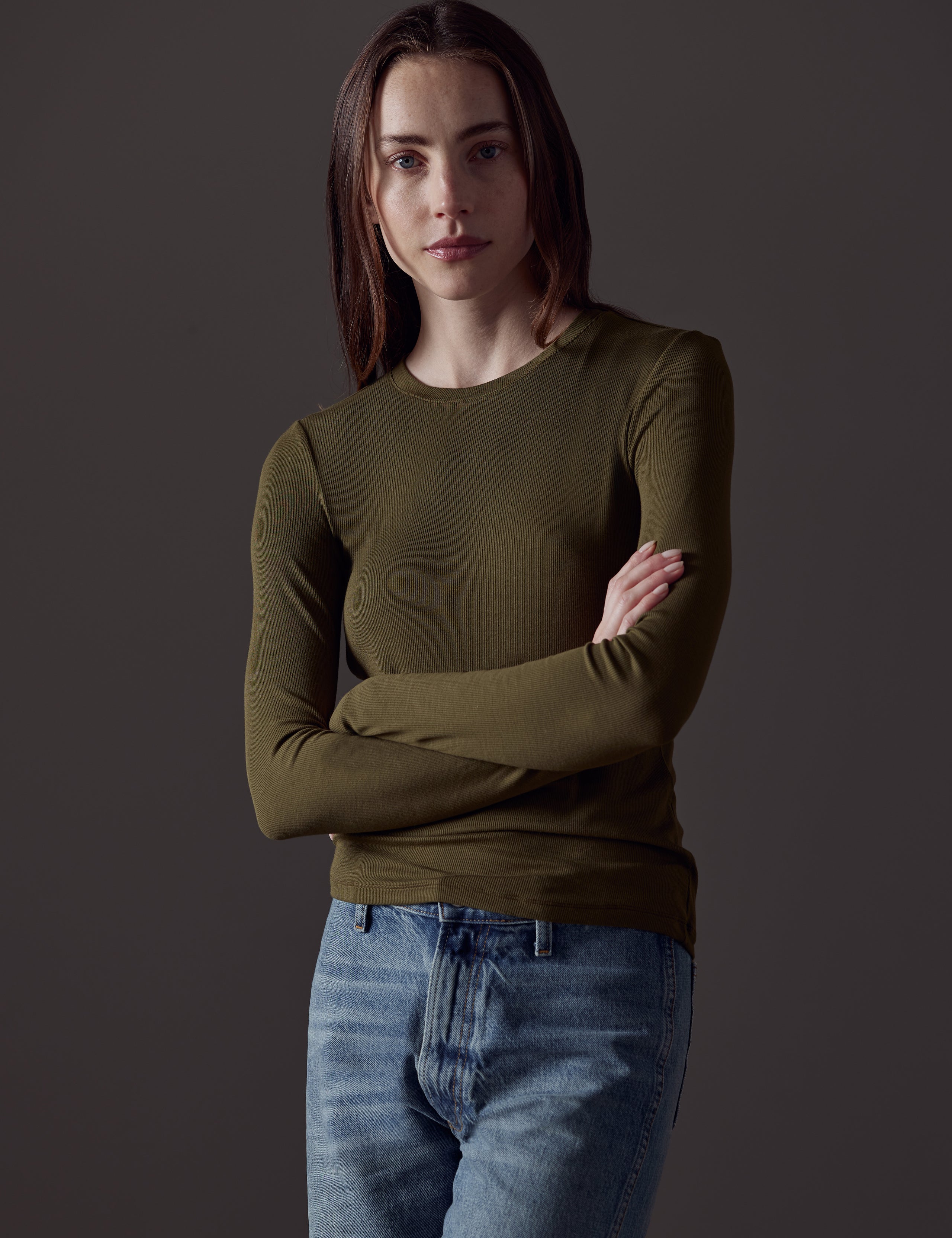 Front view of woman with arms crossed wearing Legacy Long-Sleeve Crew in Command Green from AETHER Apparel.