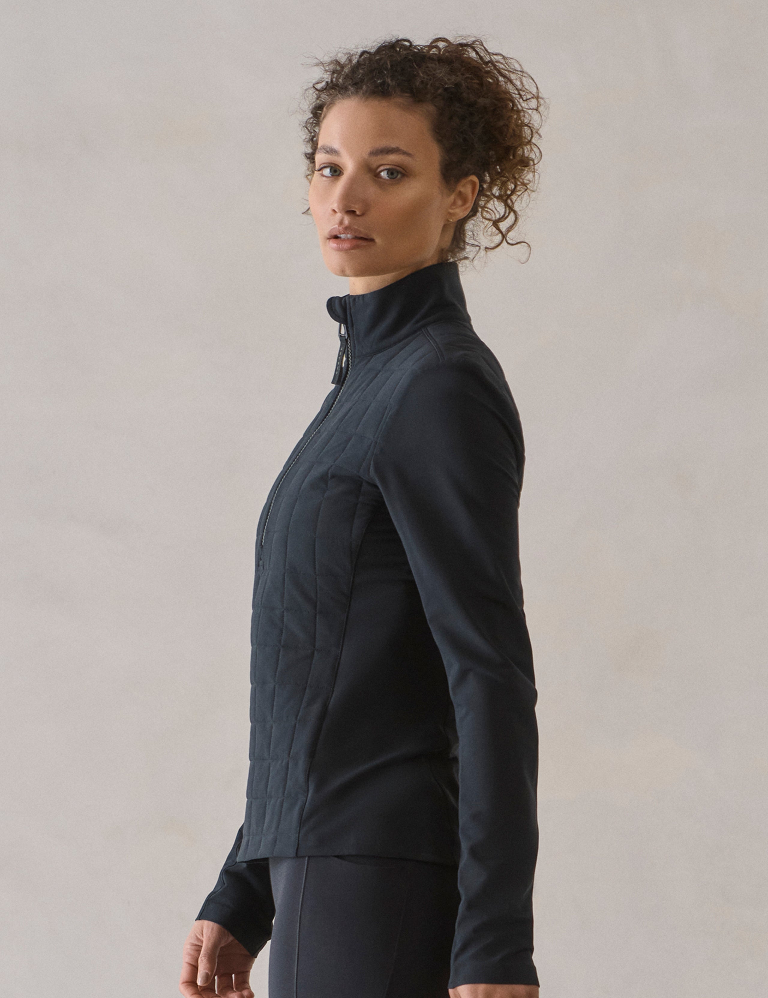 Side profile view of woman wearing Wren Insulated Half-Zip in Onyx Black from AETHER Apparel.